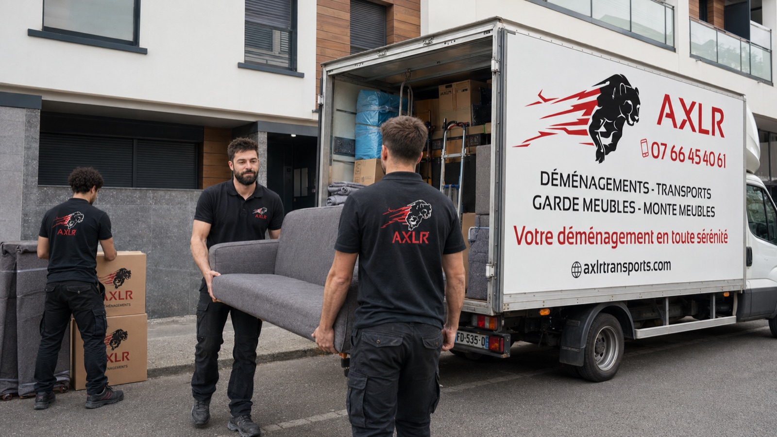 Deux déménageurs AXLR transportent un canapé protégé jusqu'au camion